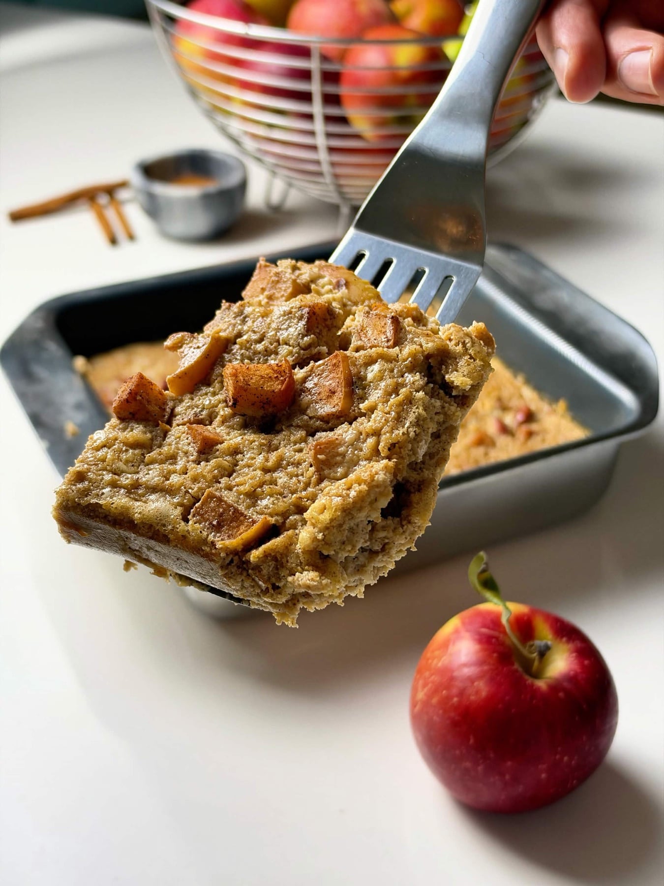 Thick slice of apple pie baked oatmeal lifted from the pan on a spatula