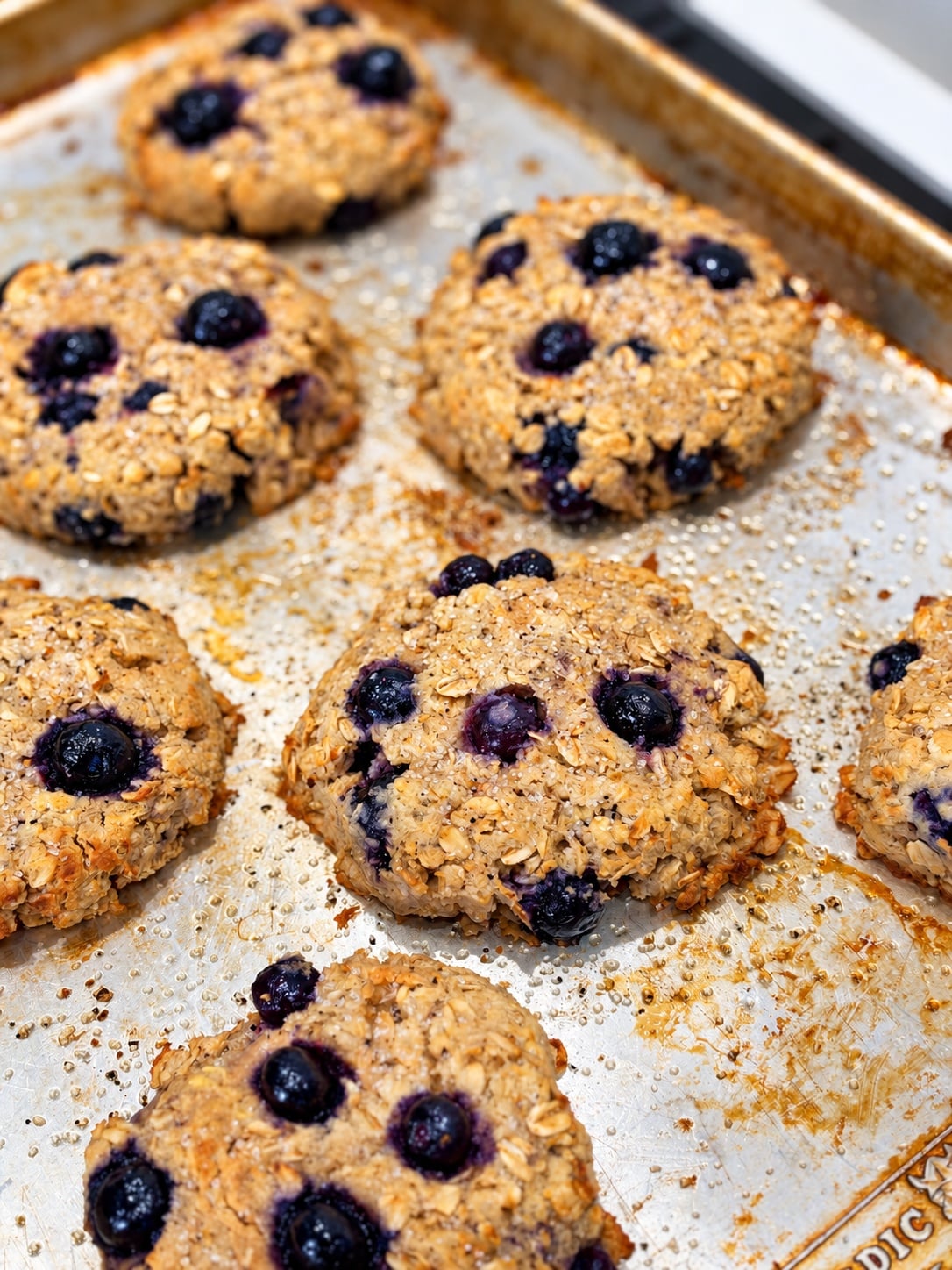 Baked blueberry oatmeal breakfast cookies with whole blueberries on a baking sheet