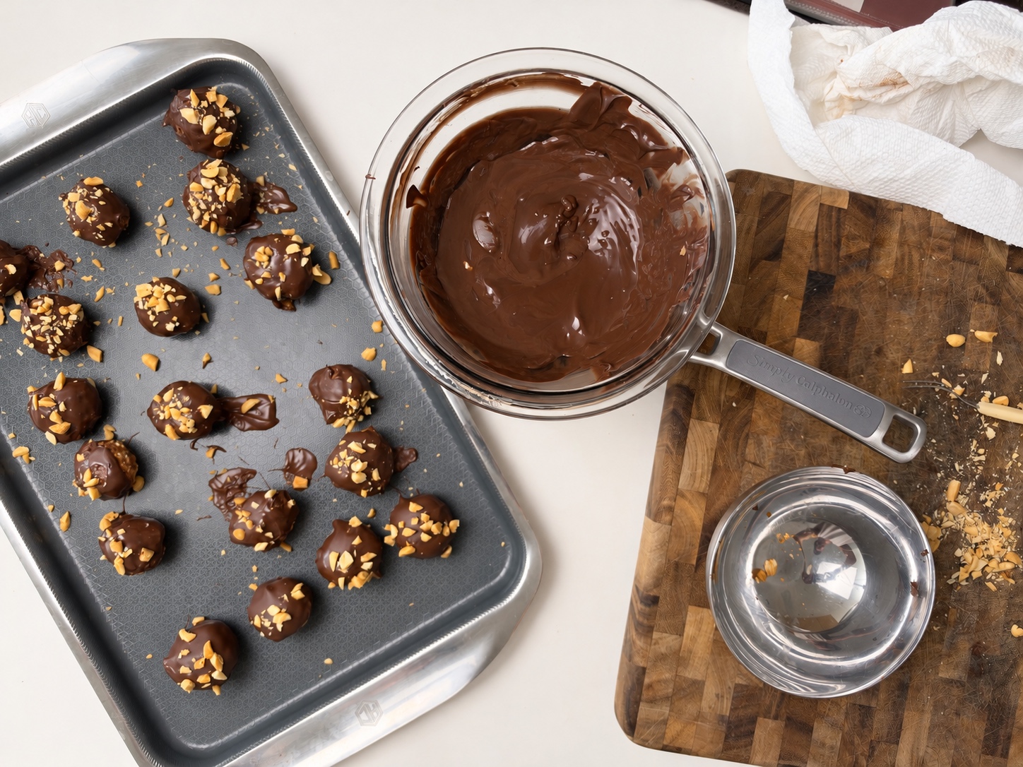 Overhead view of chocolate coating, chopped peanuts and freshly dipped protein truffles on a tray