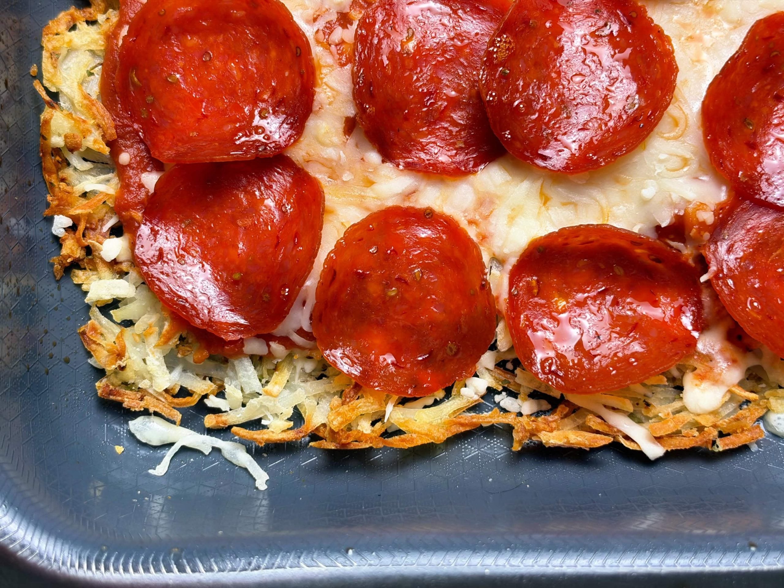 Close-up of turkey pepperoni pizza with a crisp golden hash brown edge
