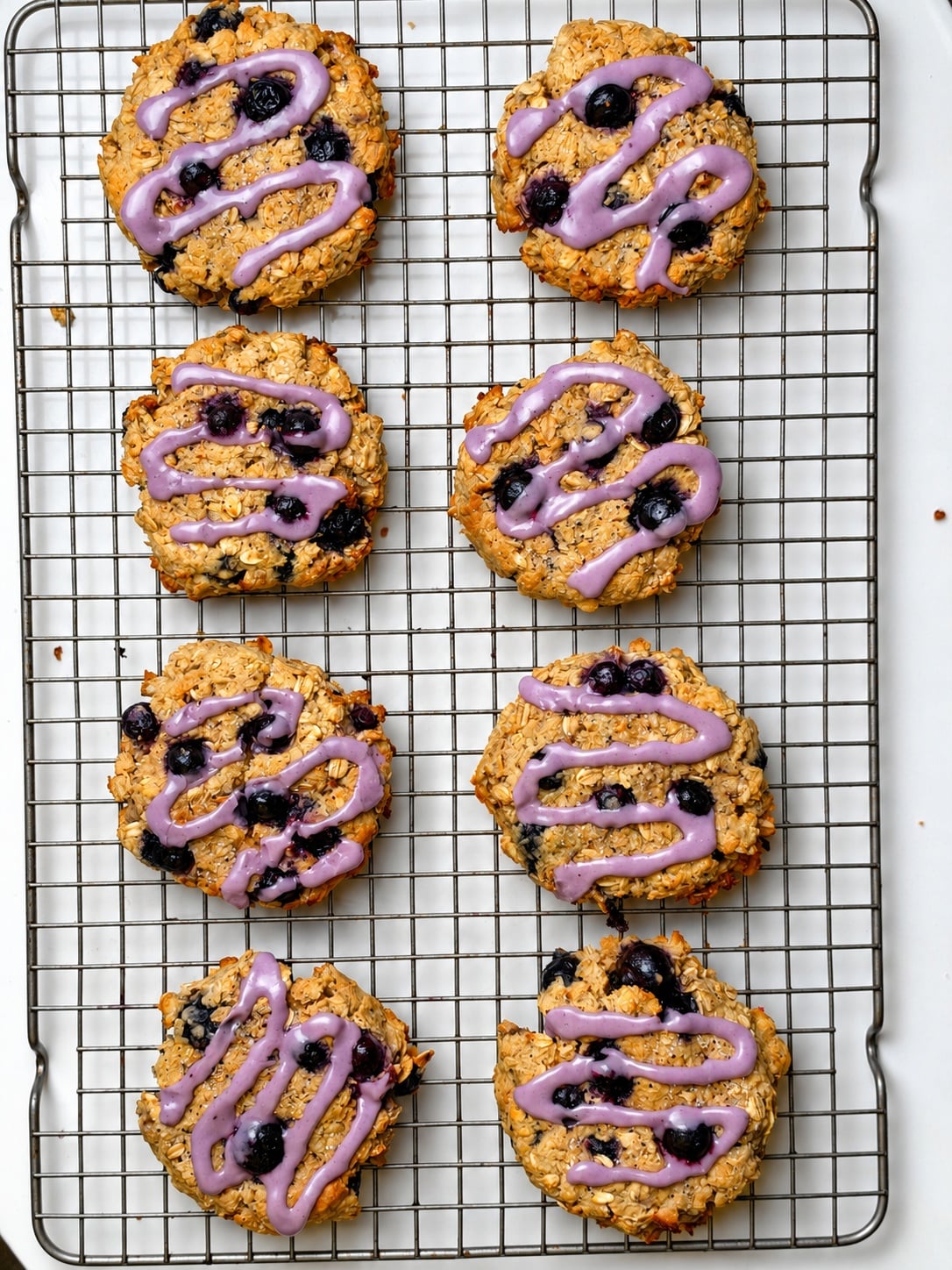 Eight blueberry oatmeal breakfast cookies topped with purple blueberry glaze