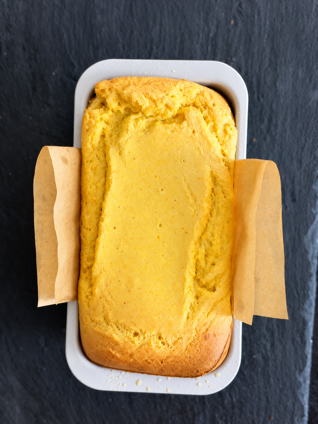Overhead view of a whole orange blender cake in a parchment-lined loaf pan