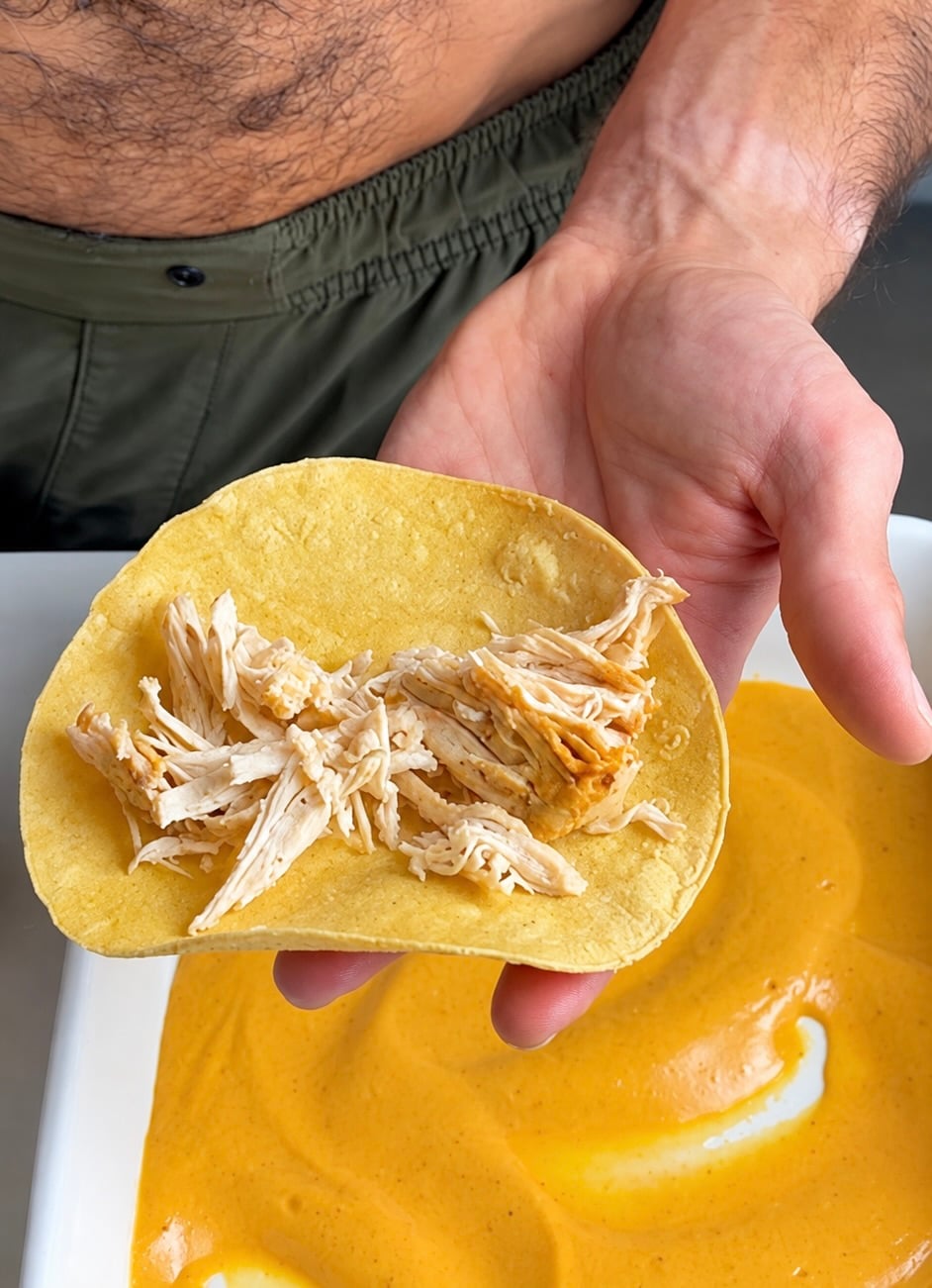 Shredded chicken placed in a warm corn tortilla over pumpkin sauce