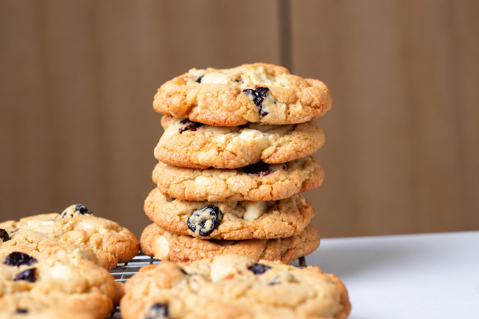 A tall stack of gluten-free white chocolate cherry almond cookies on a cooling rack.