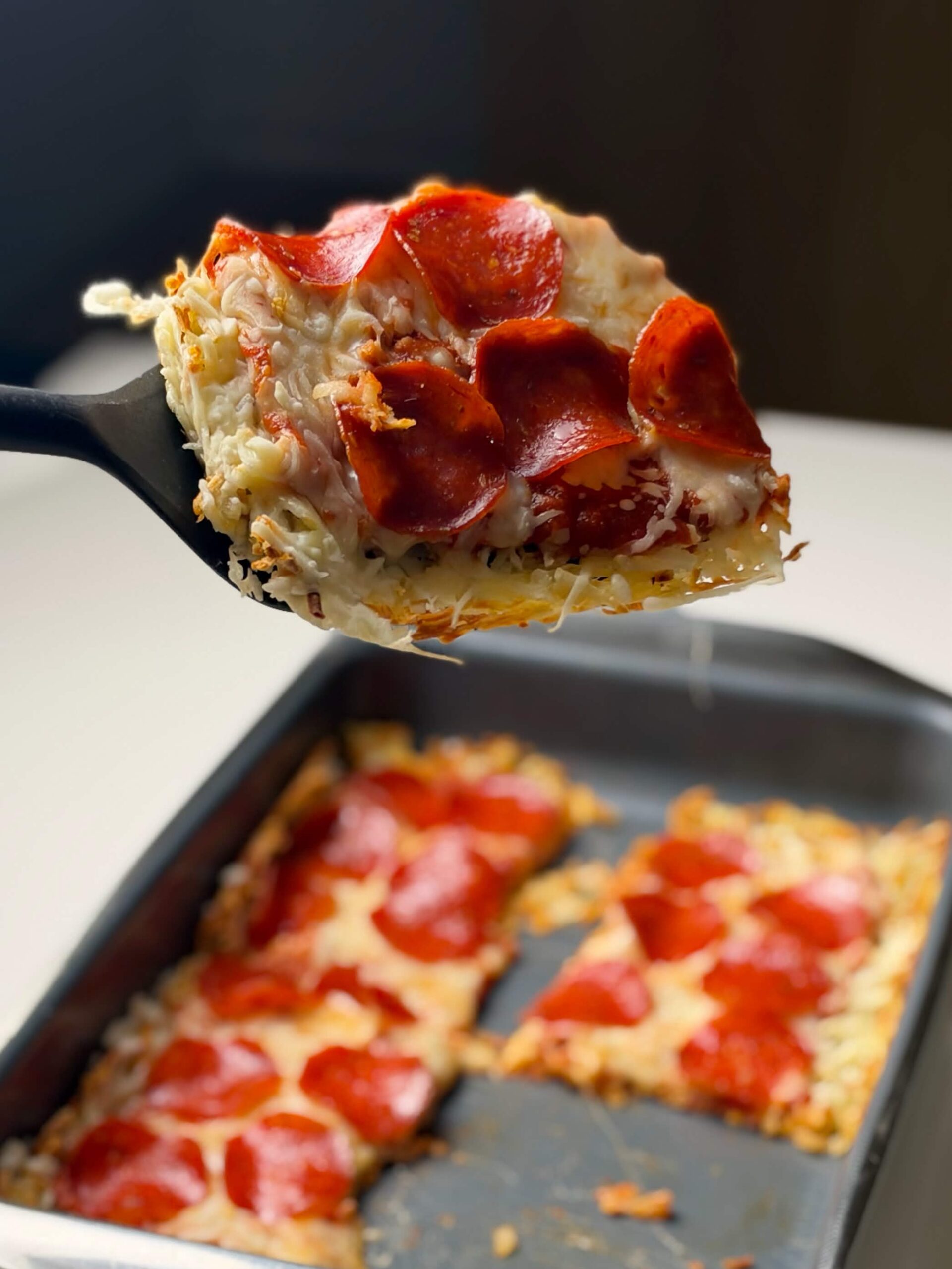Close-up of a hash brown pizza slice with mozzarella and turkey pepperoni