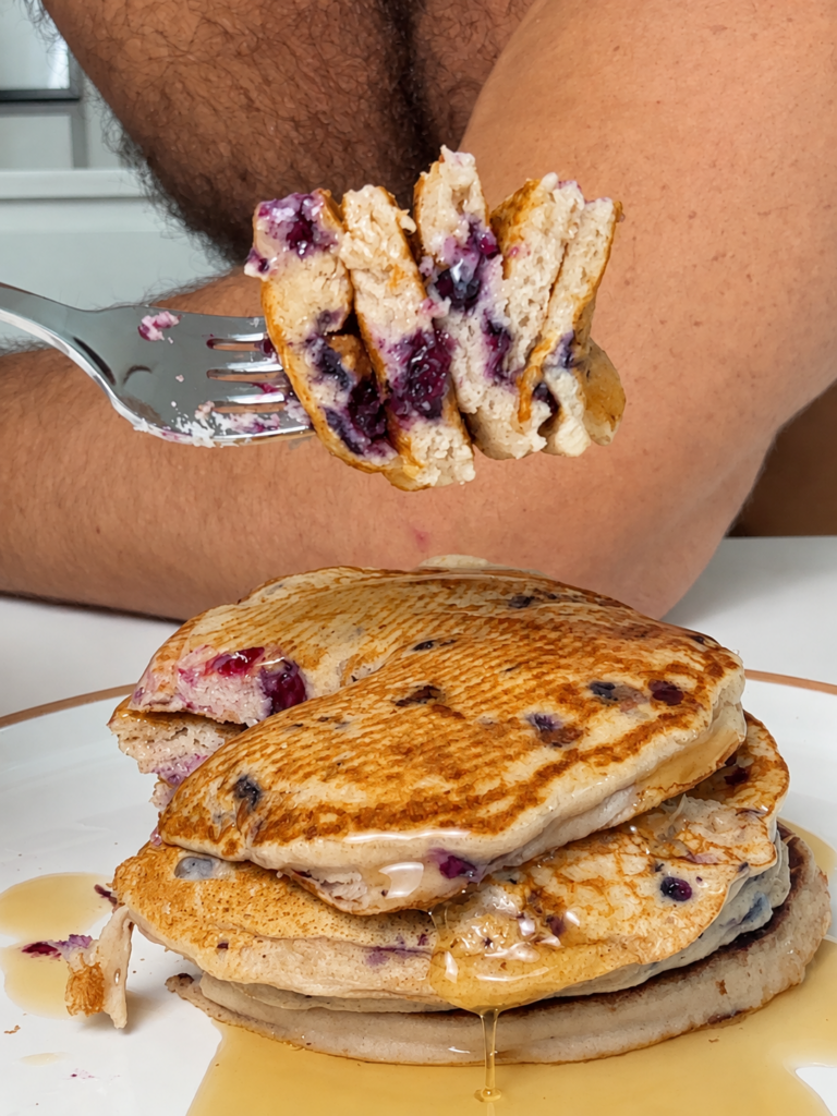 Stack of high-protein blueberry pancakes topped with syrup