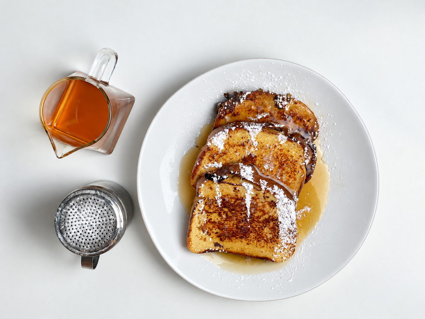 Overhead view of three slices of high-protein French toast topped with powdered sweetener and maple syrup.