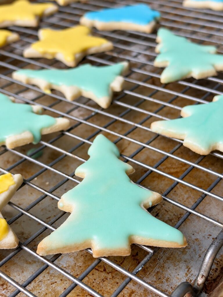 Mint green iced cream cheese sugar cookie shaped like a Christmas tree