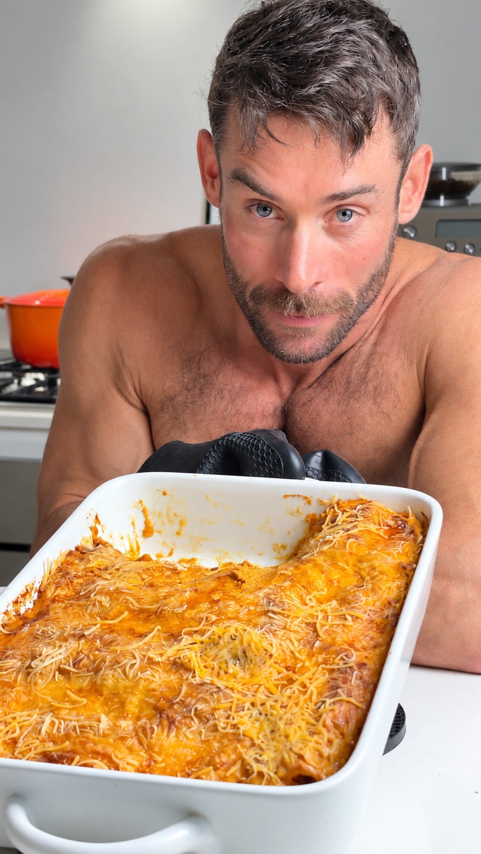 Jacob holding a pan of pumpkin chicken enchiladas in the kitchen