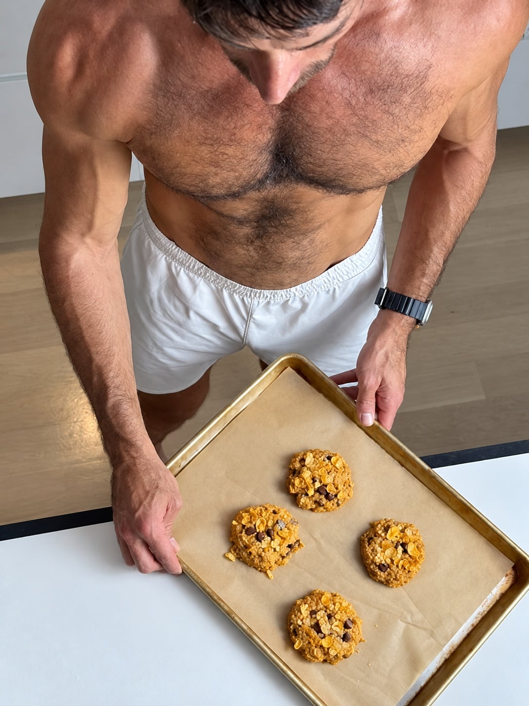 Jacob Hensley holding a baking tray with four pumpkin corn flake protein breakfast cookies