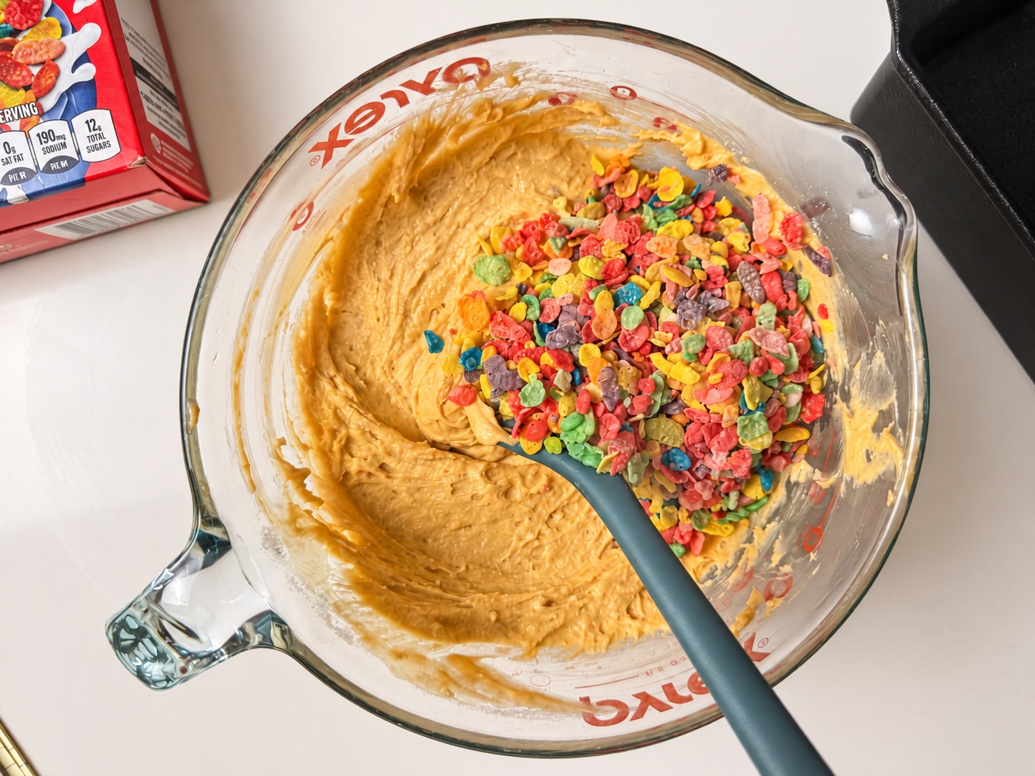 Fruity Pebbles cereal being folded into protein loaf cake batter