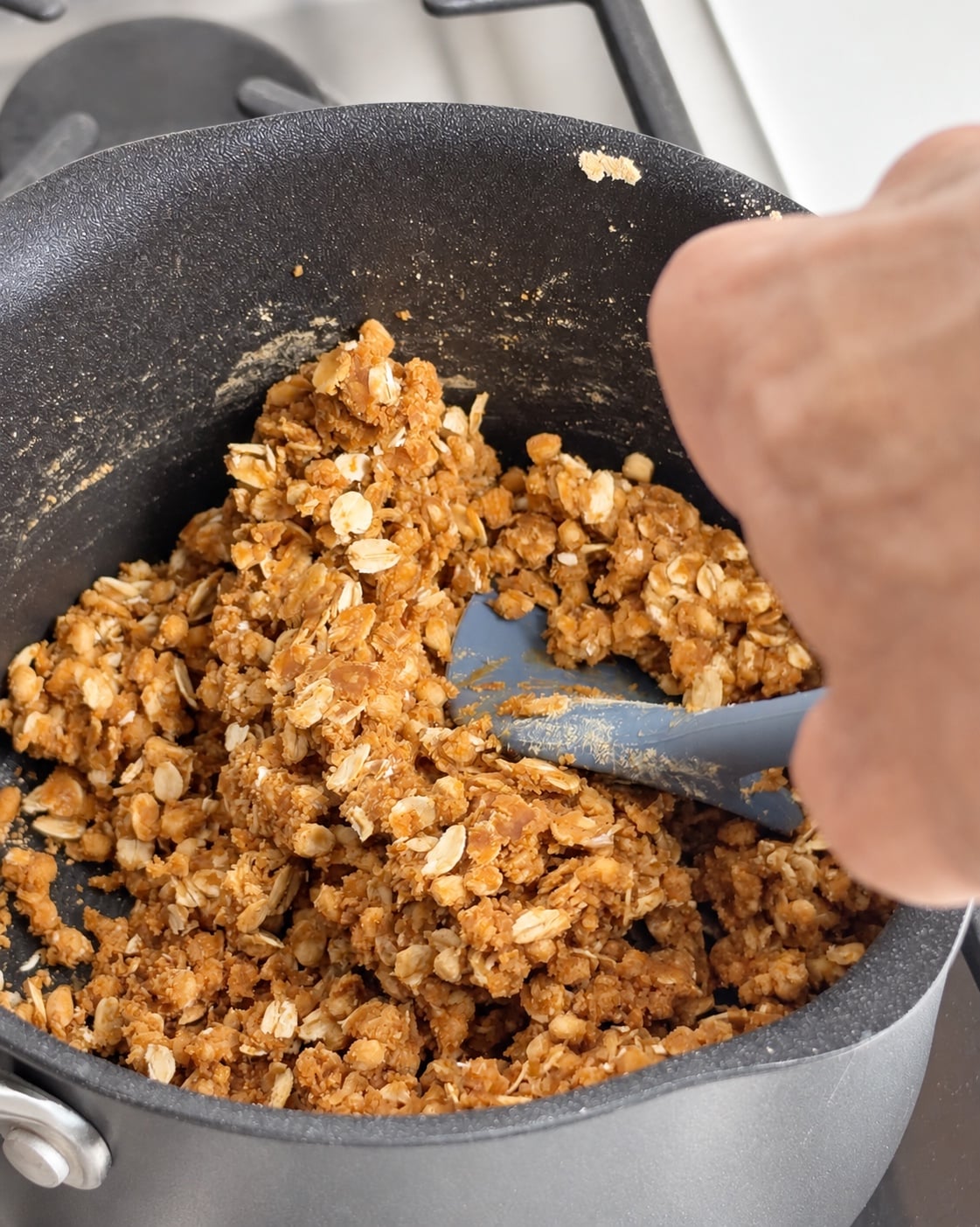 Stirring oats and powdered peanut butter into the protein truffle mixture in a saucepan