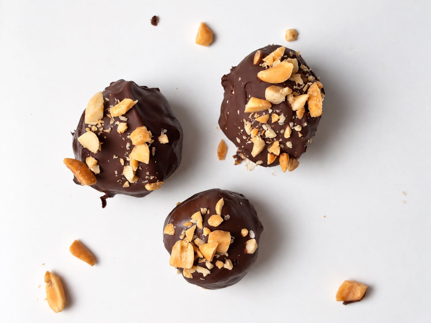 Three chocolate-coated peanut butter protein truffles viewed from overhead