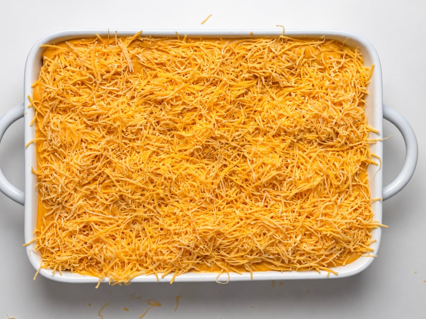 Pumpkin chicken enchiladas covered with shredded Mexican-blend cheese before baking