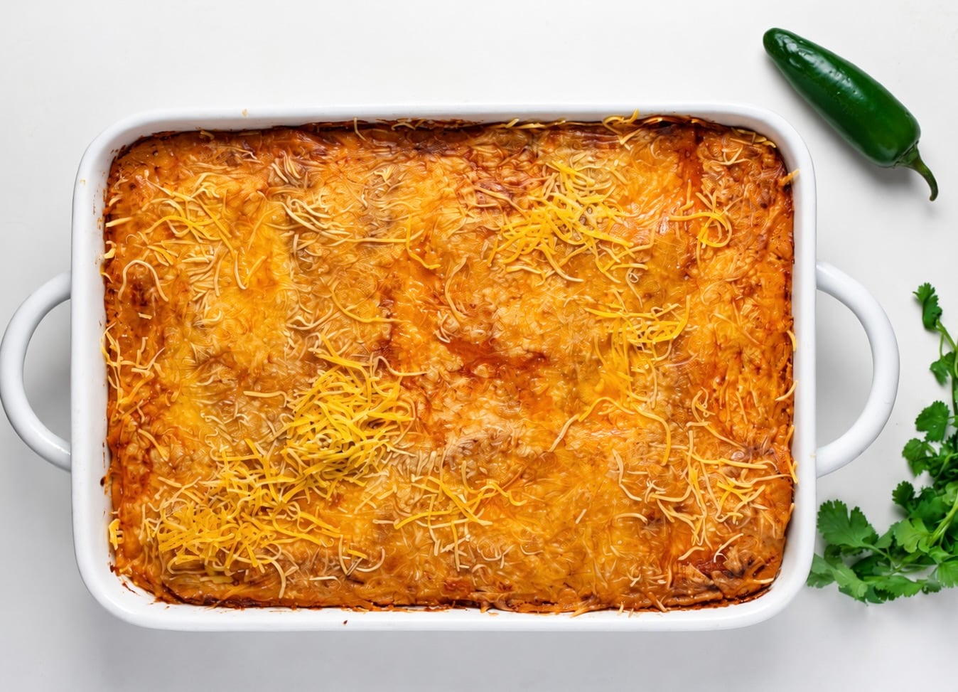 Overhead view of a full pan of baked pumpkin chicken enchiladas