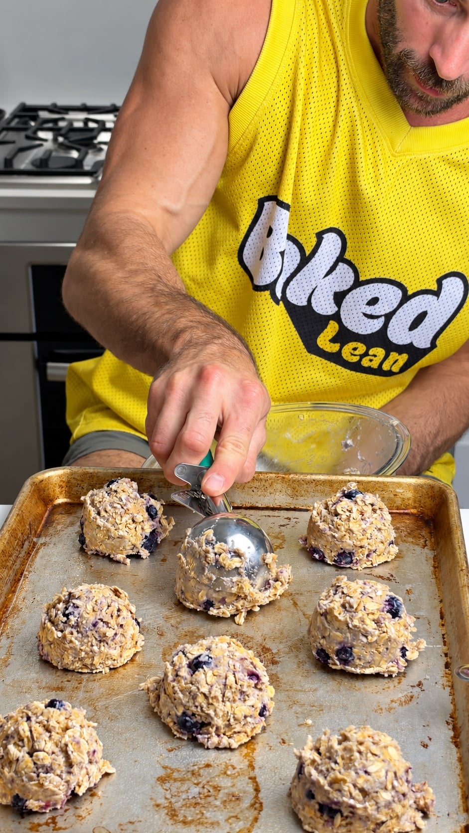 Scooping blueberry oatmeal protein cookie dough onto a baking sheet