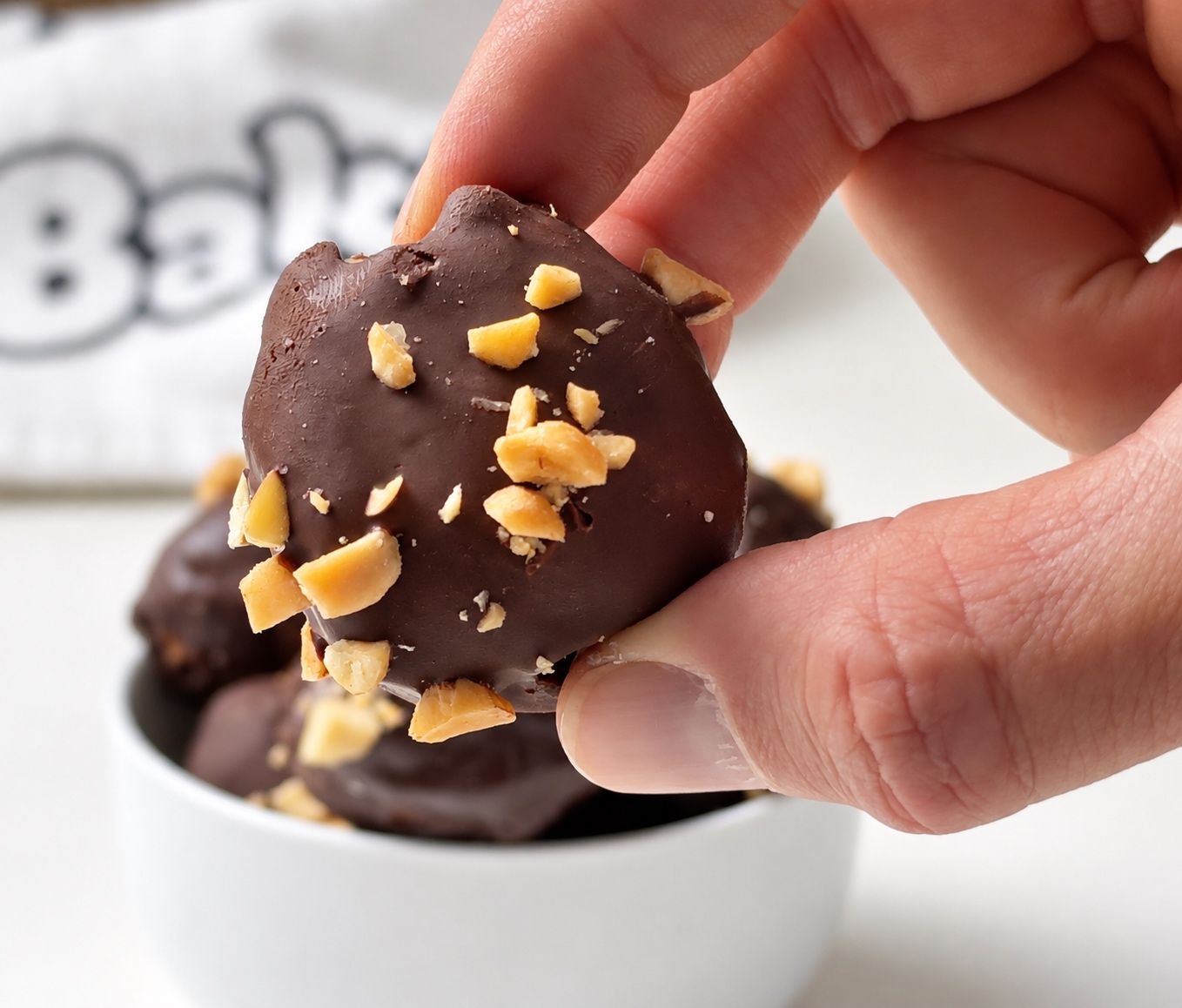 Close-up of one chocolate-coated peanut butter protein truffle topped with chopped peanuts