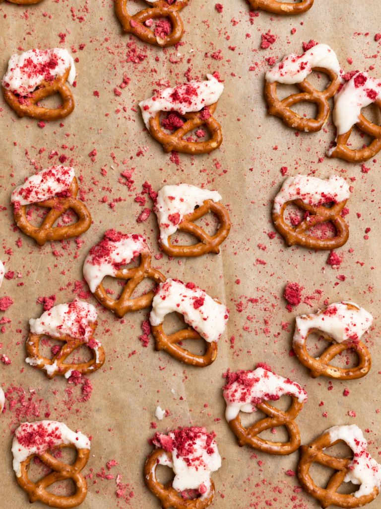 Overhead view of yogurt-covered pretzels topped with crushed freeze-dried strawberries on parchment paper