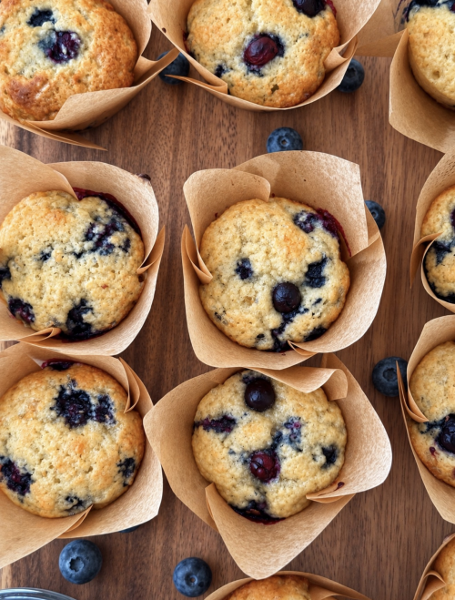 Overhead view of golden blueberry cottage cheese muffins in parchment liners with fresh blueberries