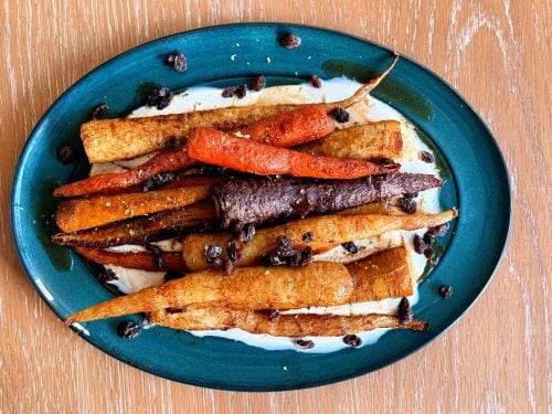 Close-up of roasted carrots with a harissa maple glaze over yogurt