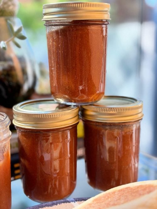 Homemade apple butter stored in glass jars with gold lids.