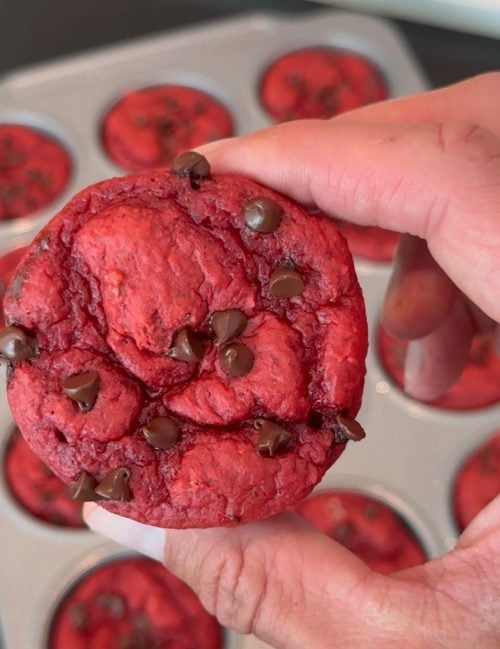 Hand holding a red velvet protein cupcake with chocolate chips