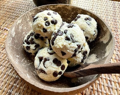 High-protein no-bake cookie dough served in a coconut bowl with chocolate chunks on top.