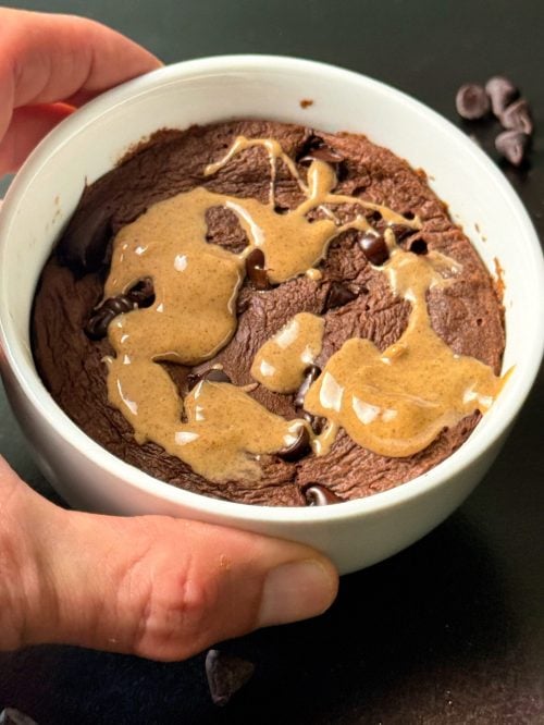 holding microwave chocolate brownie with peanut butter drizzle