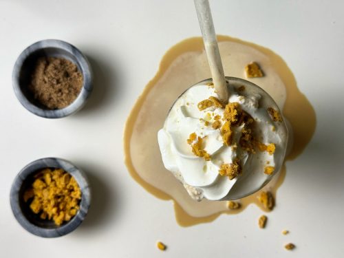 Overhead view of pumpkin spice protein frappé with whipped cream, cookie crumbs, and pumpkin spice