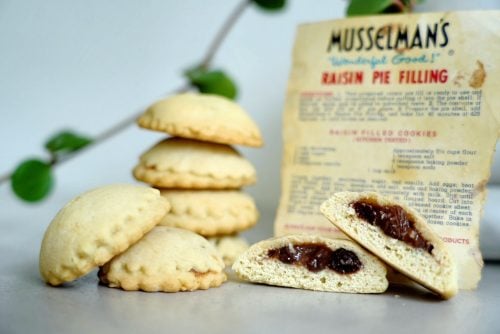 Raisin filled cookie cut open to show jammy raisin filling with vintage recipe card in the background.