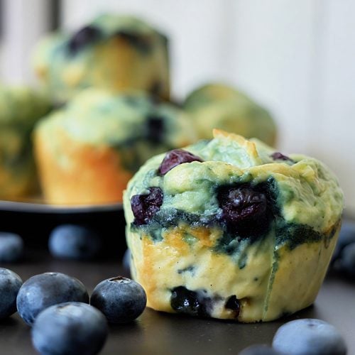 Fluffy low-calorie blueberry muffins with golden tops and bursting blueberries, cooling on a wire rack.